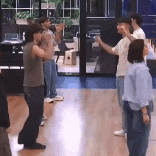 a group of people are dancing in a room .