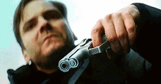 a man is holding a gun in his hand and looking at it .