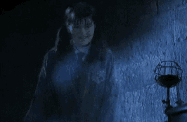 a person is standing in a dark room with a lamp in the background