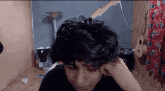a person with a black shirt on is looking down at their hair