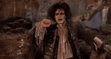 a zombie is standing in the dirt with his arms outstretched and screaming .