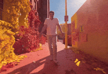 a man in a white shirt is walking down a street with a sign on the wall that says ' italy ' on it
