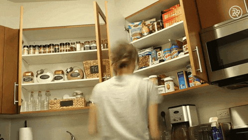 a woman reaches into a pantry with a bag of kraft macadamia nuts on the shelf