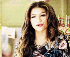 a woman with long hair is wearing a floral top and necklace