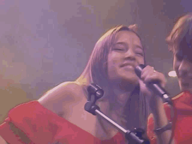 a woman is singing into a microphone while a man looks on
