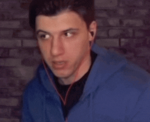 a young man wearing headphones and a blue hoodie is looking at the camera .