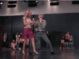 a man and a woman are dancing on a stage in front of a crowd .
