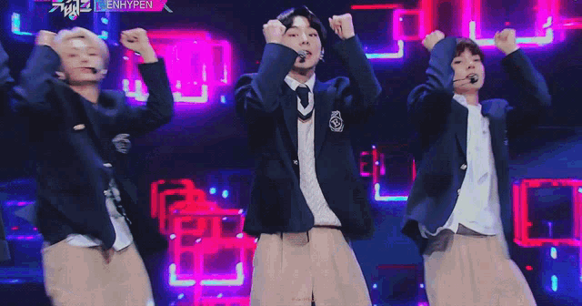 a group of young men in school uniforms are dancing on a stage
