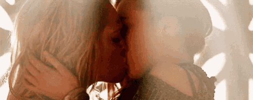 a couple of women are kissing each other on the cheek .
