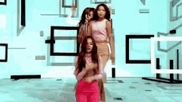 a group of women are dancing in a room with geometric shapes on the wall