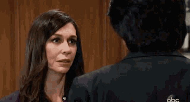 a man in a suit is touching a woman 's face in a room .