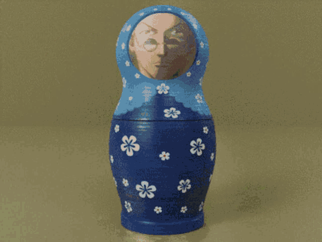 a blue green and orange russian nesting doll with a man 's face on it