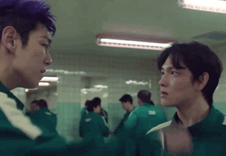 two men are standing next to each other in a hallway .