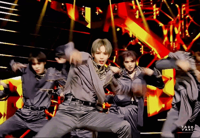 a group of young men are dancing on a stage with taro yaki written on the bottom right