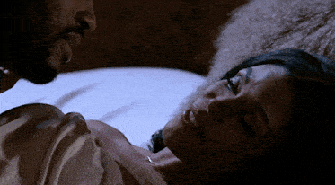 a man and a woman are laying on a bed and the man is looking at the woman