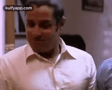 a man in a white shirt is making a funny face while standing next to another man .