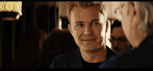 a man in a suit is smiling and looking at another man