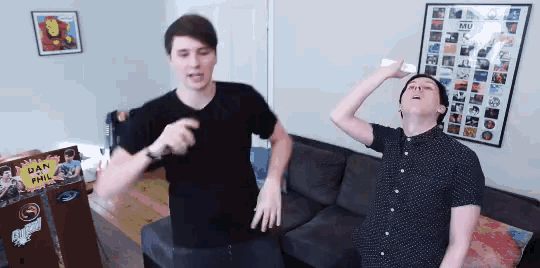 two men are dancing in front of a poster that says dan and phil on it
