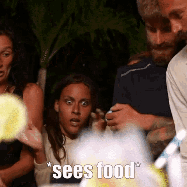 a group of people are standing around a table and one of them says " sees food * "