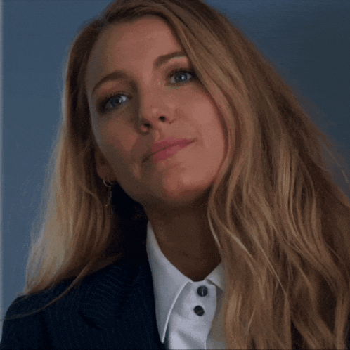 a woman with long blonde hair is wearing a white shirt and a suit