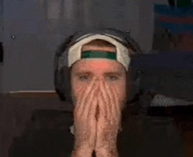 a man wearing headphones and a hat covering his face with his hands .