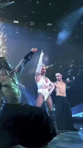 a group of people are dancing on a stage and one of them is giving the middle finger