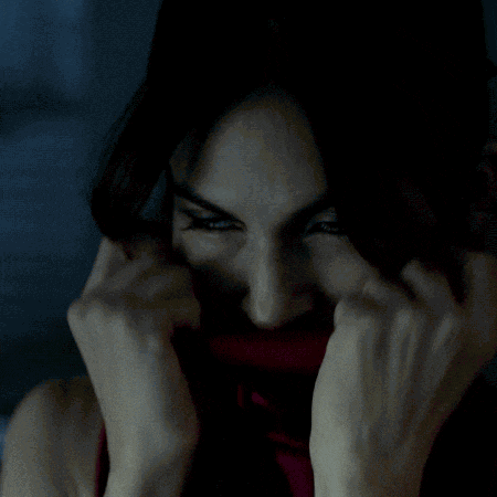 a woman covering her face with her hands and looking at the camera
