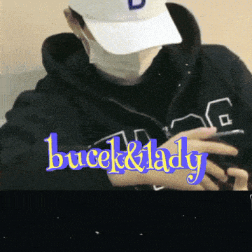 a man wearing a mask and a hat is holding a cell phone and the words bucek & lady are above him