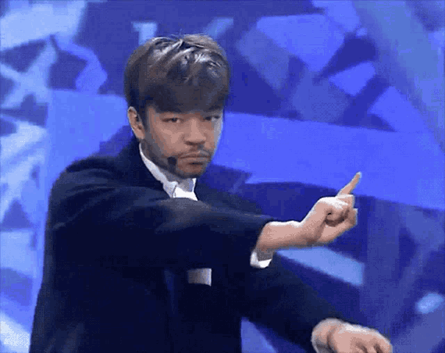 a man in a tuxedo is pointing his finger at something