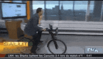 a man is riding a bike in front of a tv screen that says salut on it