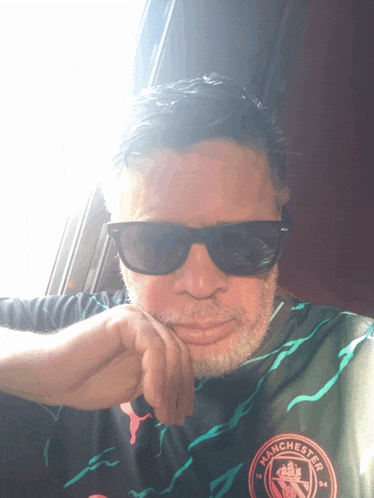 a man wearing sunglasses and a shirt with the word manchester on it
