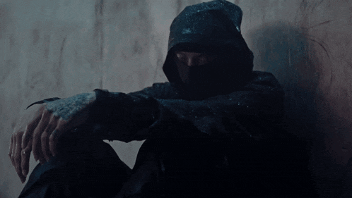 a man with a tattoo on his hand is wearing a black hooded sweatshirt