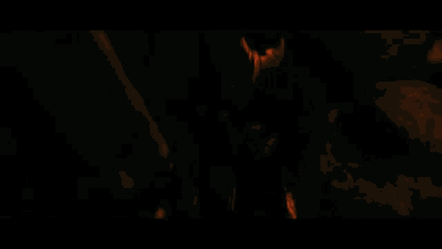 a group of people are standing in a dark room with their hands in the air .