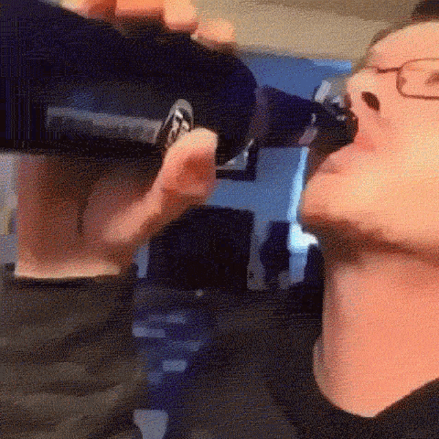 a man is drinking a bottle of beer from a bottle .