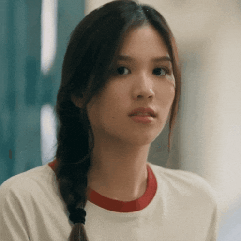 a woman with braided hair and a white shirt with a red collar