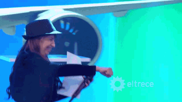 a man in a top hat is holding a piece of paper in front of an airplane and the word eltrece