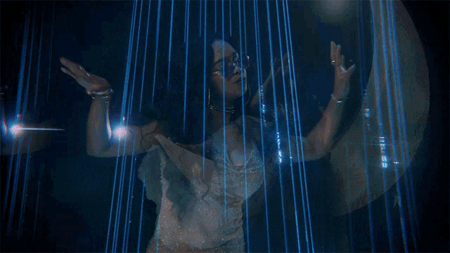 a woman wearing sunglasses and a choker is dancing in front of a blue light