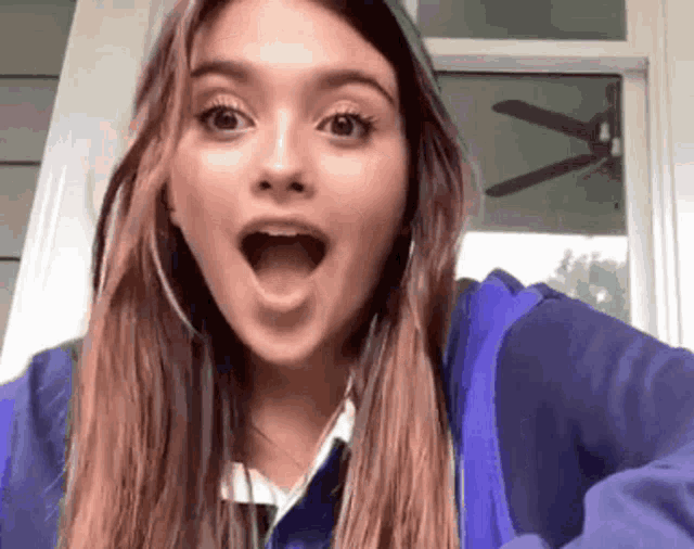 a girl with a surprised look on her face wearing a blue jacket