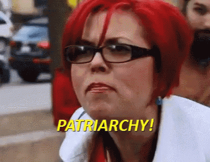 a woman with red hair and glasses is saying patriarchy !