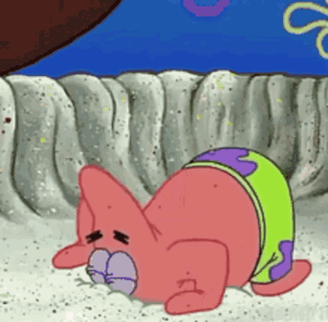 patrick star from spongebob squarepants is laying on his back on the sand .