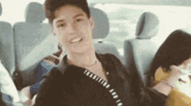 a young man is sitting in the back seat of a car with other people .