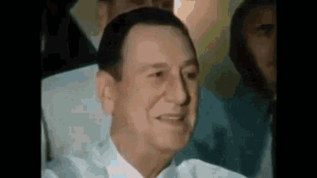 a close up of a man in a suit and tie smiling while sitting in a chair .