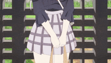 a woman in a plaid skirt is standing in front of a black fence