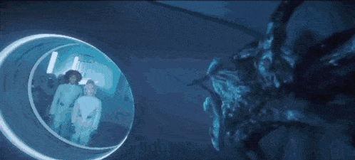 a group of people are standing in a tunnel and looking at a giant bug .