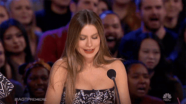 a woman in a strapless dress is speaking into a microphone in front of a crowd with nbc written on the bottom right