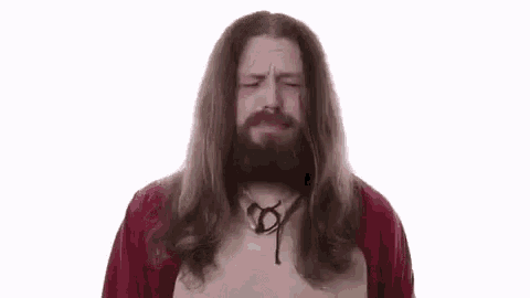 a man with long hair and a beard is dressed as jesus and praying .