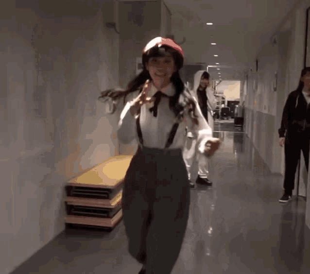 a woman wearing a red beret and a white shirt is walking down a hallway