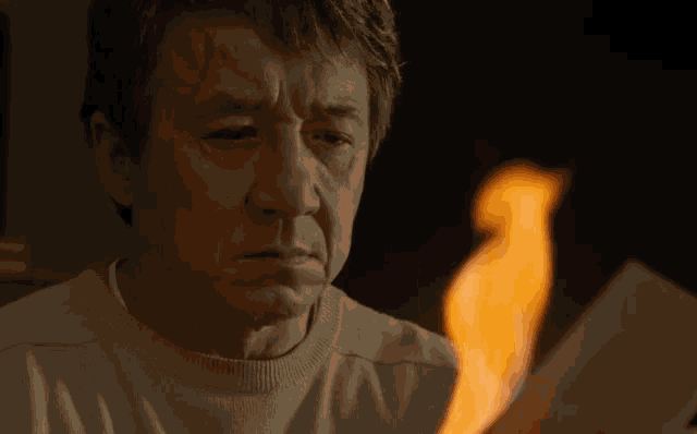 a man looks at a piece of paper that is on fire