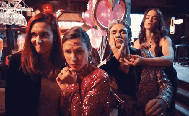 a group of women are posing for a picture in front of balloons and a sign that says ' stella artois '