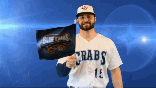 a man in a blue crabs jersey holds up a small flag